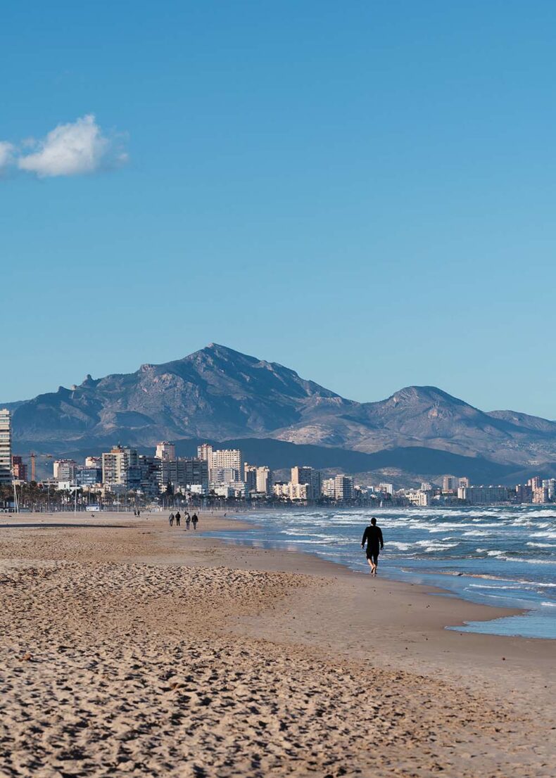 A man walking at San Juan Beach with a mountain view