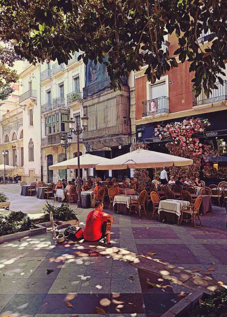 People enjoy their meal with musician playing on the street