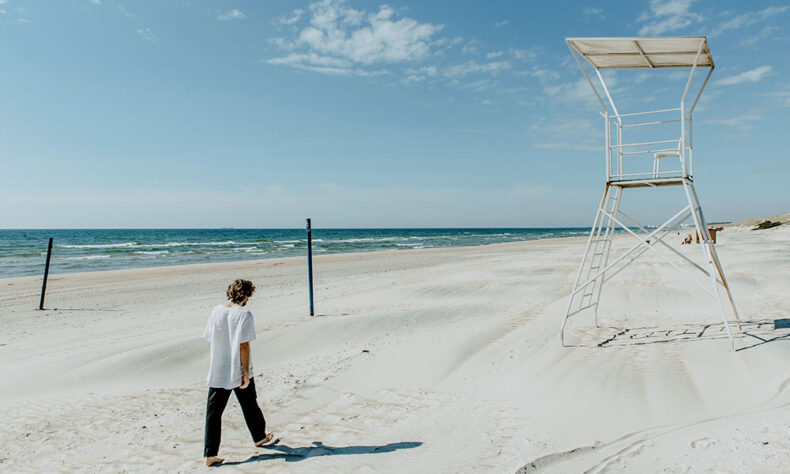 A man walking at the white sand beach in Palanga