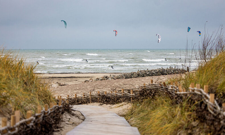 White sand beach and the kiteboarders in the sea in Lithuania