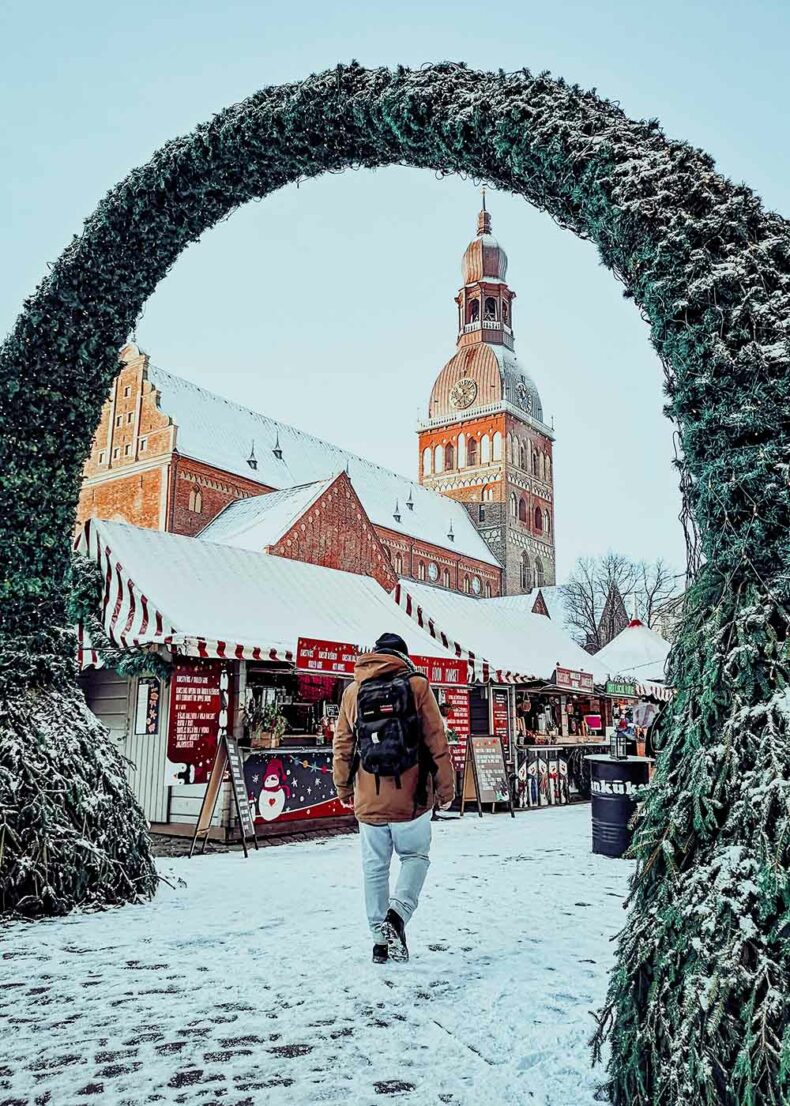 A man entering Riga Christmas market through spruce branches gate