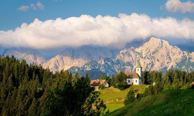 Church of the Holy Spirit in Slovenia on a hill with mountains in the background