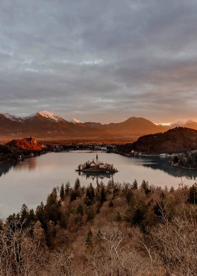 The tall Julian Alps in the background, and a tiny island with a church in the middle of Lake Bled