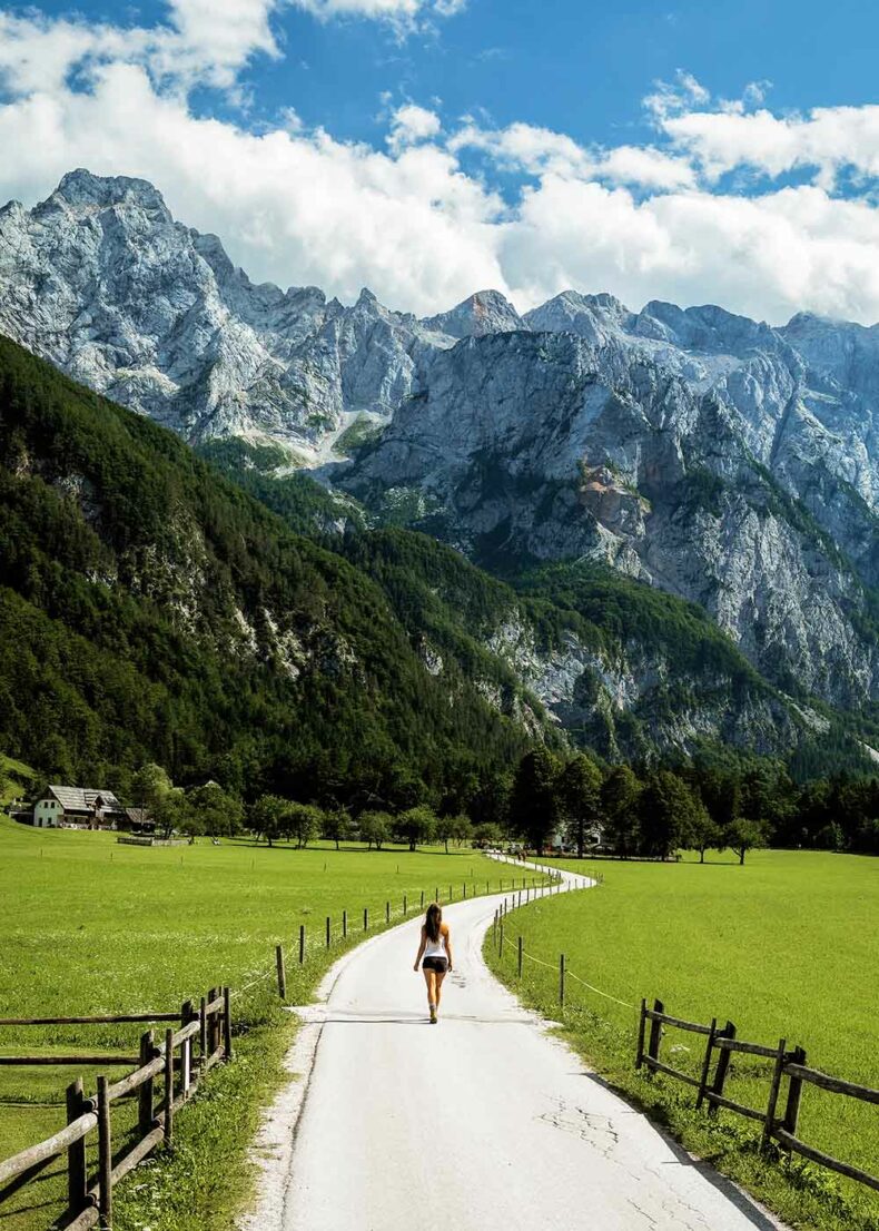 Woman walking at the Logar Valley with breathtaking mountains view in the background