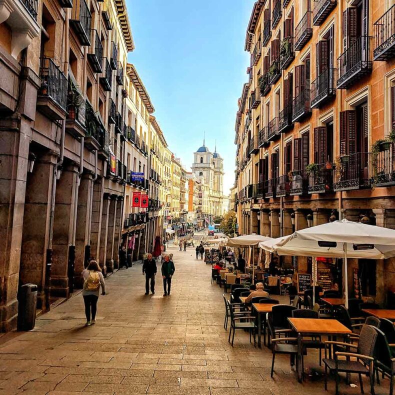 Narrow street of Madrid with cafes during sunny daytime