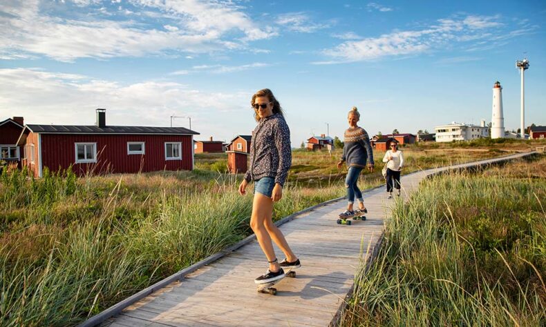 View to seaside wooden houses and women on longboards at the Hailuoto Island