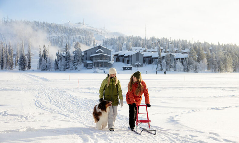 Two women walking with dog in winter in Kuusamo
