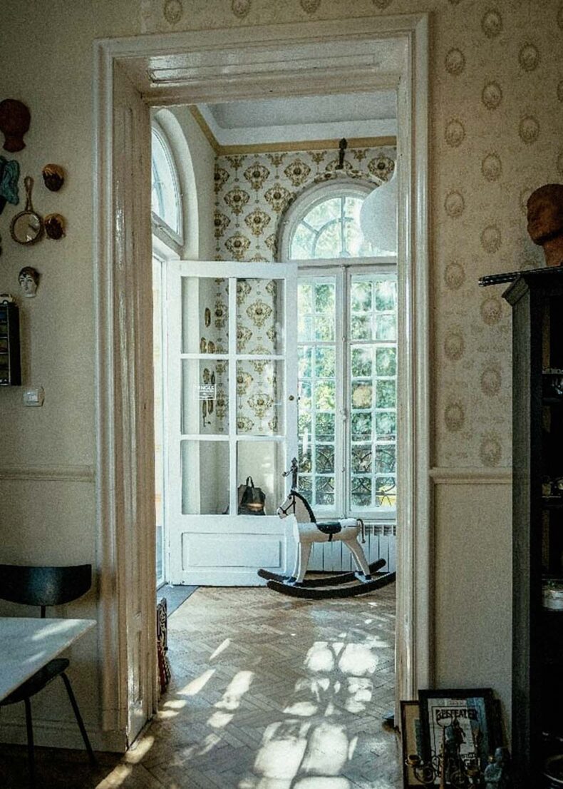 The interior of Mingle – Vintage & Coffee Shop classic wooden windows, vintage-style wallpaper, and a wooden rocking horse